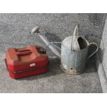 A galvanised aluminium watering can and a red painted Jerry can.