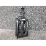 A black painted metal and wooden ship's pulley.