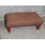 Rectangular shaped upholstered footstool, on brass castors