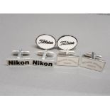 3 pairs of cufflinks in the style of Nikon, Titleist & Franck Muller Geneve