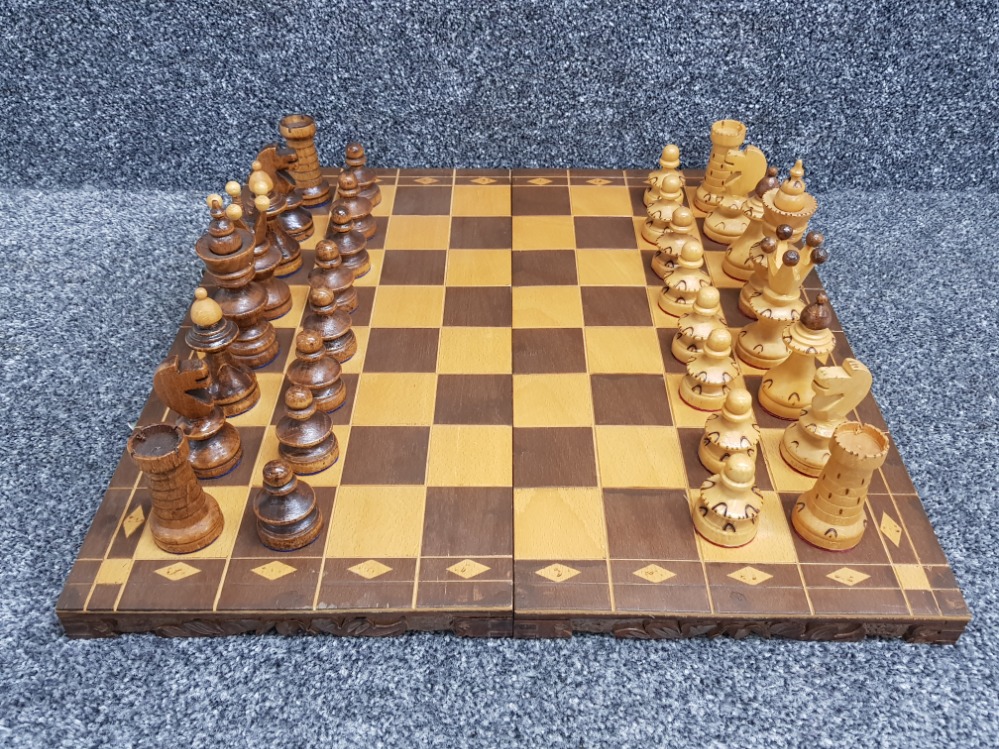 Large wooden travel chess board with carvings to base, complete with hand carved wooden pieces