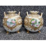 A pair of Noritake twin handled squat vases both raised on tripod feet with gilt & floral
