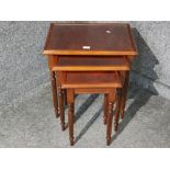 A reproduction mahogany nest of tables with glass inserts.