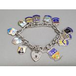 A silver charm bracelet with heart shaped clasp, and various enamel tourist charms, most being