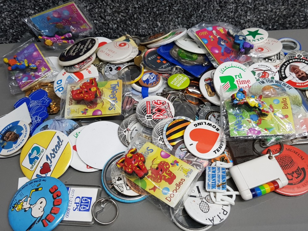 A large collection of badges, pogs, keyrings etc