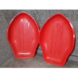 Two large red plastic toboggans