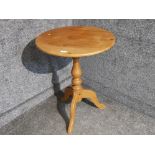 A pine circular occasional table raised on tripod legs.