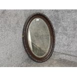 A carved mahogany framed oval bevelled glass wall mirror 84 x 57cm