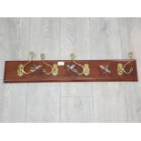 A carved wooden and brass coat rack