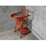 An antique child's red painted wooden high chair