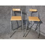 A pair of laminate and metal folding breakfast bar stools