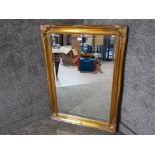 A modern bevelled wall mirror with gold swept frame 106 x 76cm