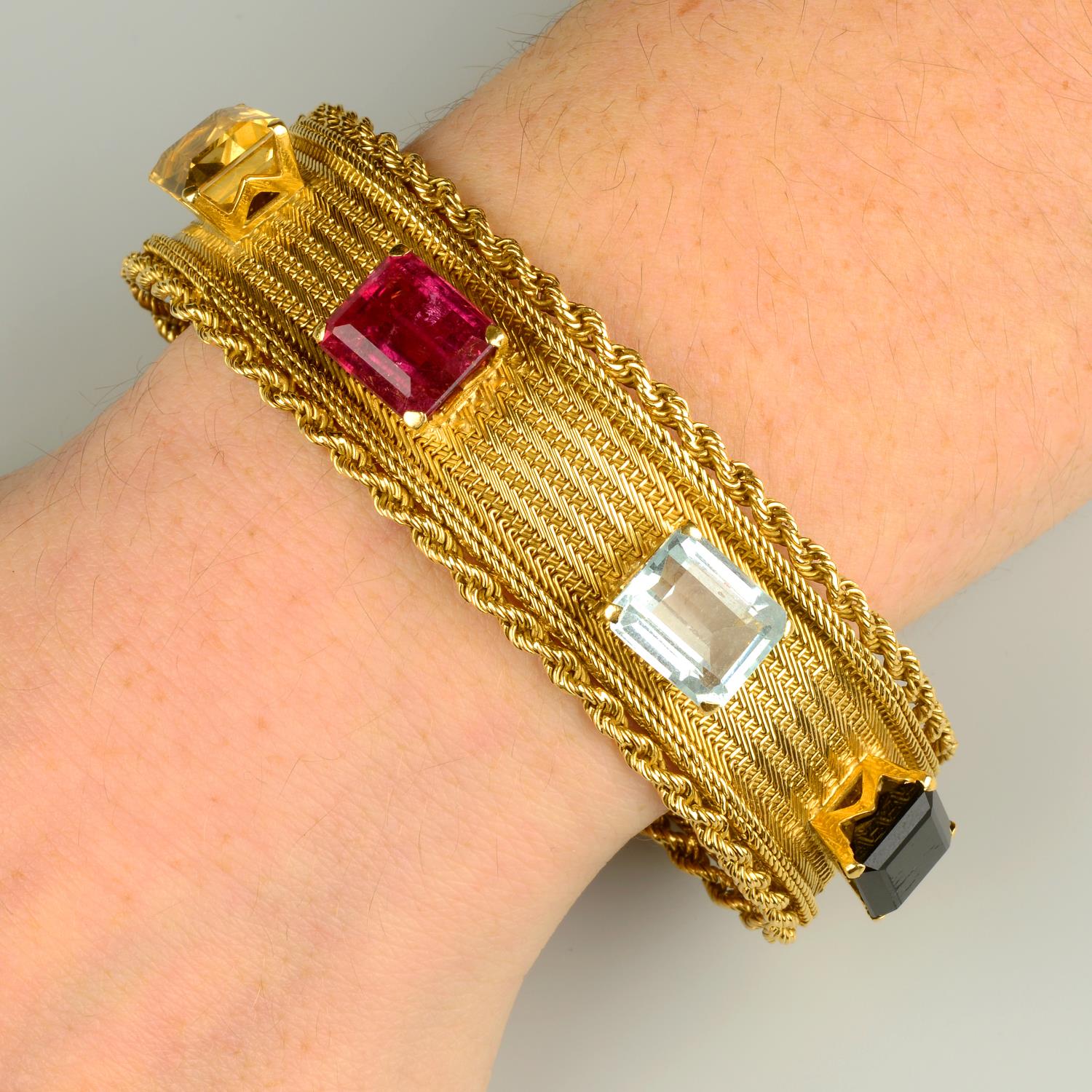 A mid 20th century 18ct gold multi-gem woven-link bracelet.Pink tourmaline calculated weight