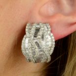 A pair of brilliant and baguette-cut diamond interwoven line motif earrings.Total diamond weight