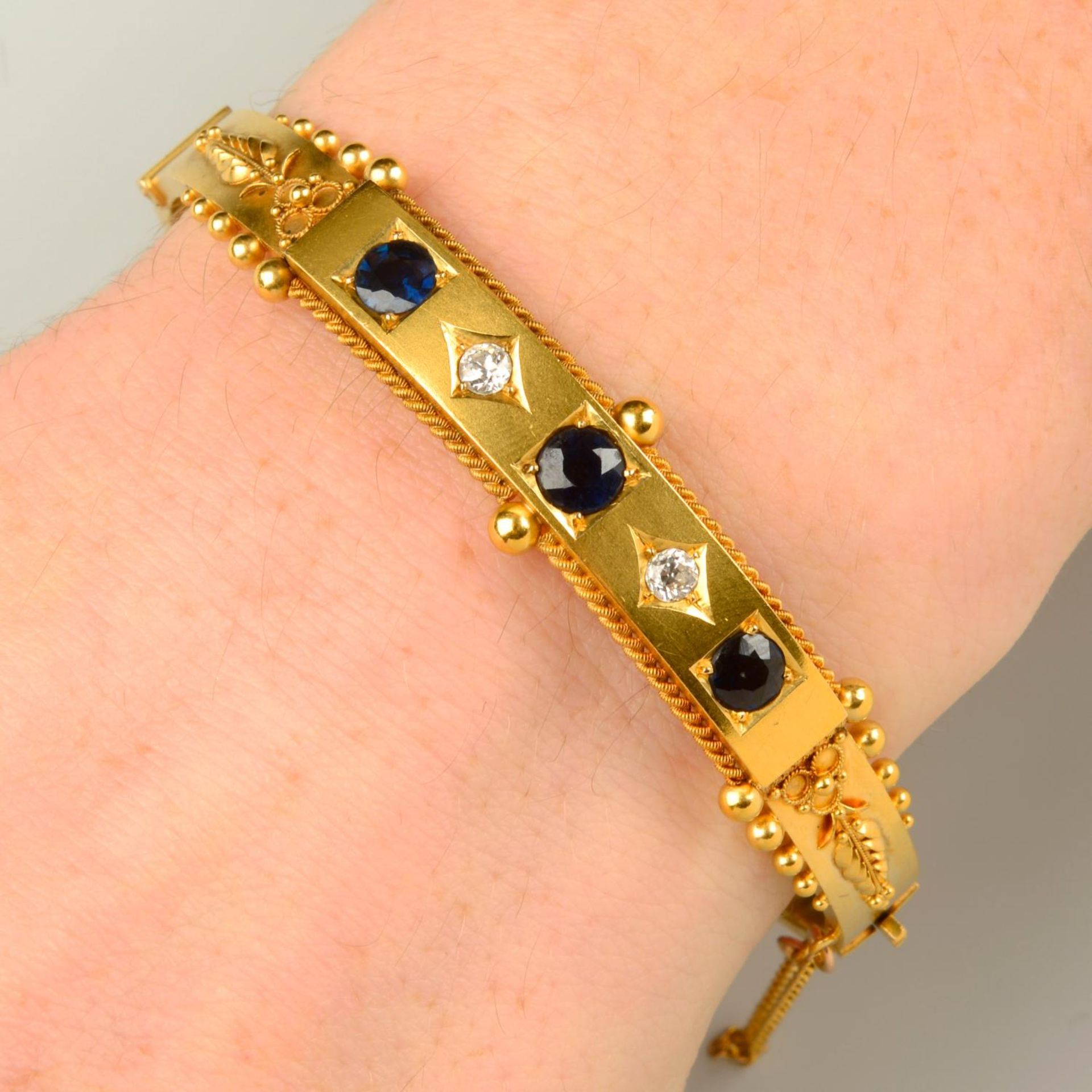 An early 20th century 15ct gold sapphire and circular-cut diamond hinged bangle,