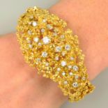 A 1970's textured openwork 18ct gold and scattered brilliant-cut diamond hinged bangle,