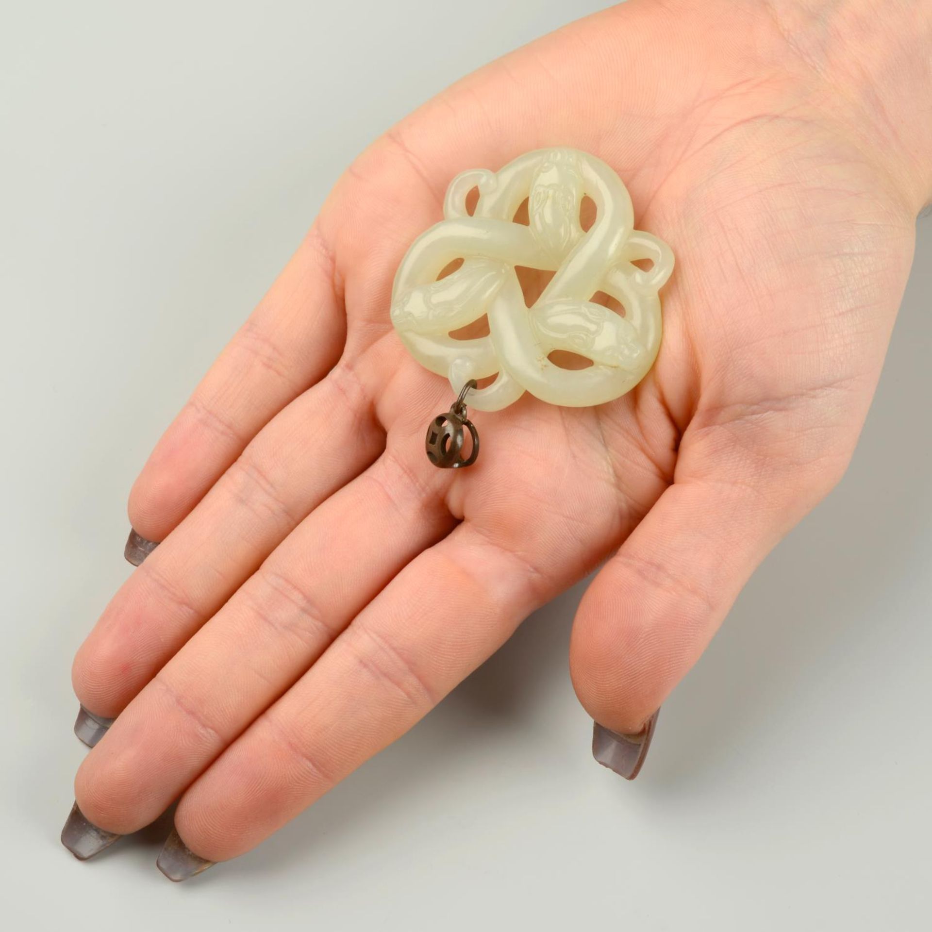 A carved Celadon jade pendant, designed as three entwined dragons, possibly Qing Dynasty.