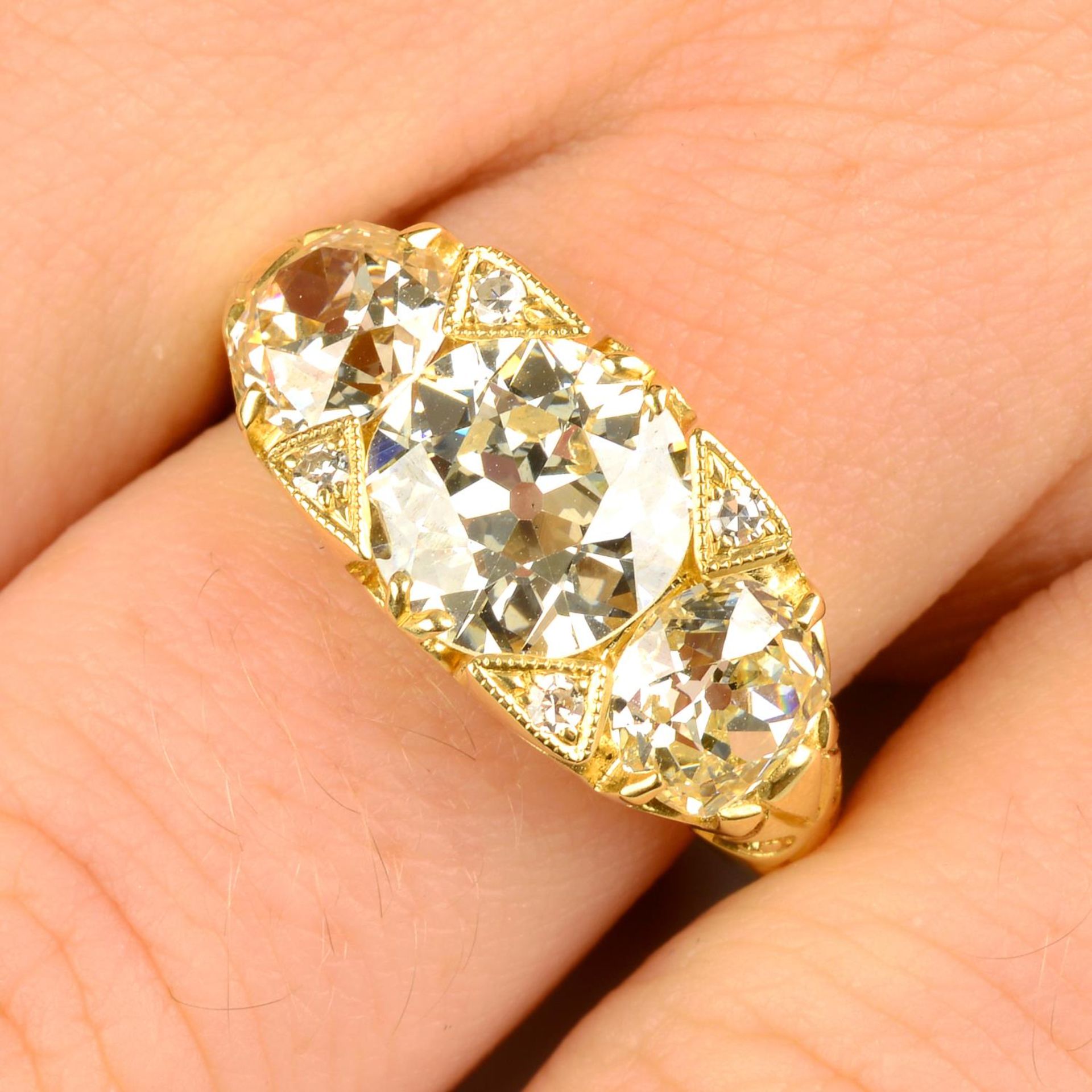 A graduated old-cut diamond three-stone ring, with single-cut diamond accents.