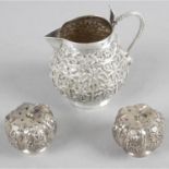 Four assorted items in white metal to include a cream jug, a salt and pepper and a pair of tongs.