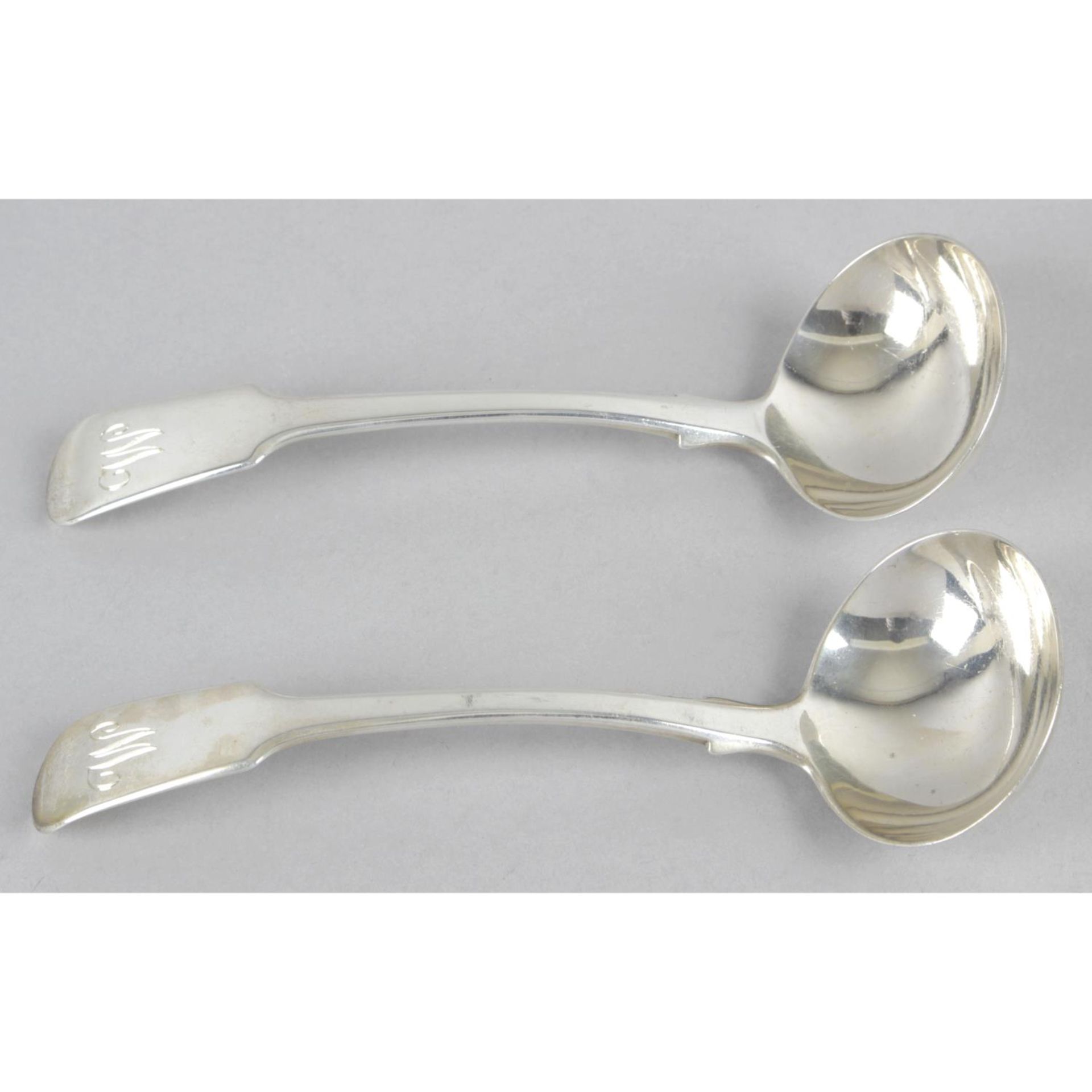 A pair of late George III silver sauce ladles, in Fiddle pattern with initial engraved terminals.