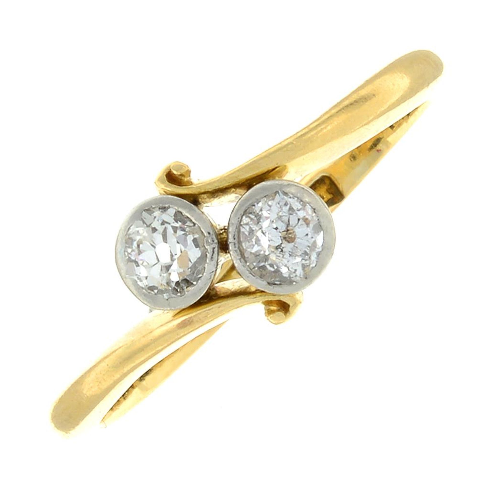 An early 20th century 18ct gold old-cut diamond two-stone crossover ring.Estimated total diamond