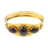 A late 19th century garnet cabochon bangle, hinged to the plain reverse.