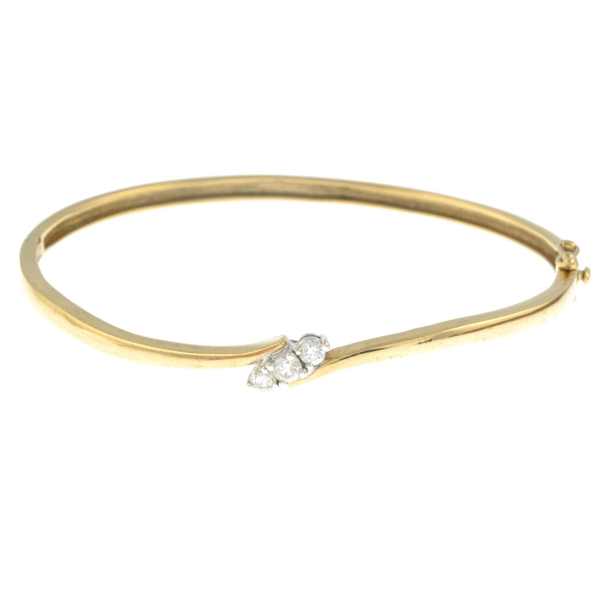 A 9ct gold brilliant-cut diamond three-stone hinged bangle.Estimated total diamond weight 0.20ct,