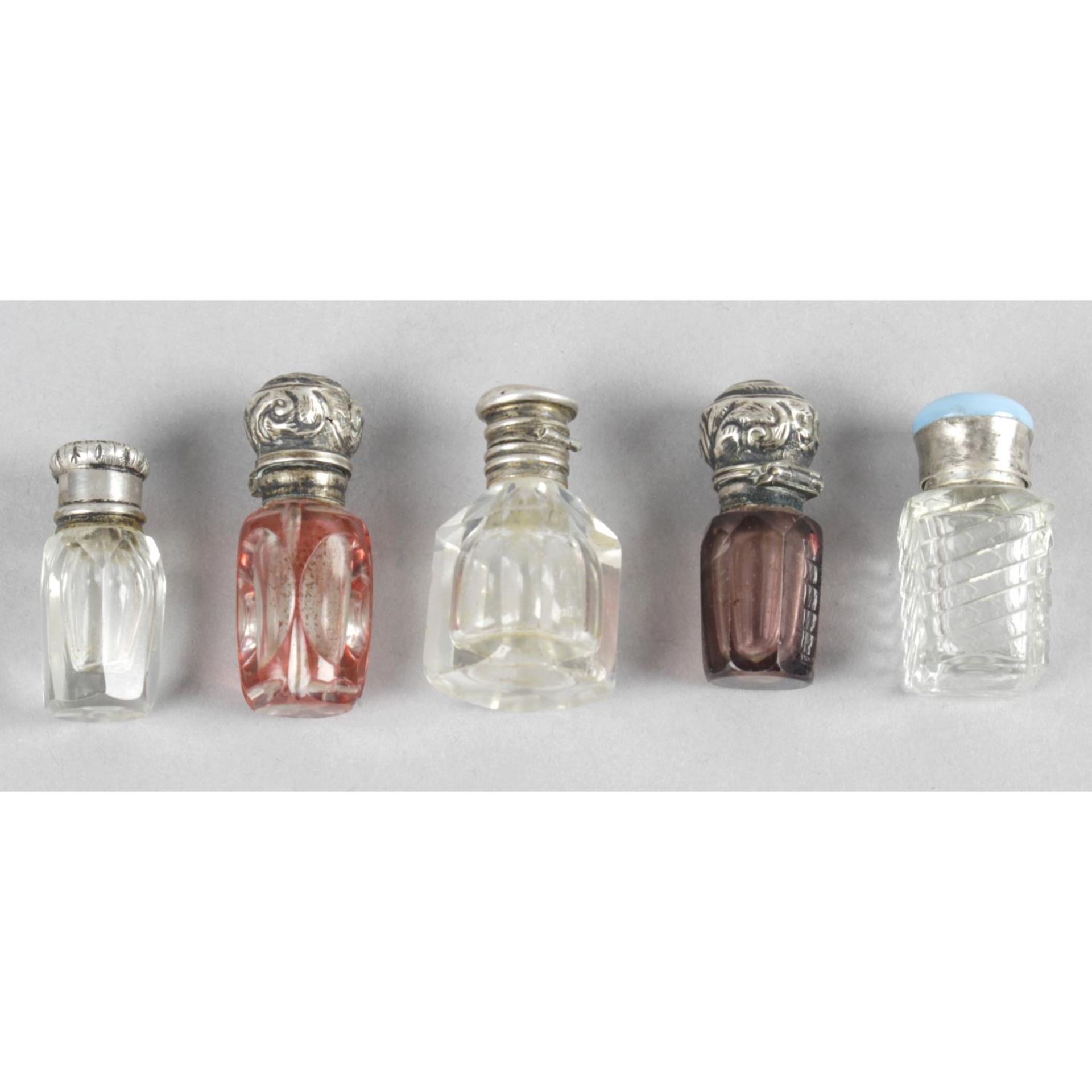 A selection of five white metal mounted miniature glass scent bottles,