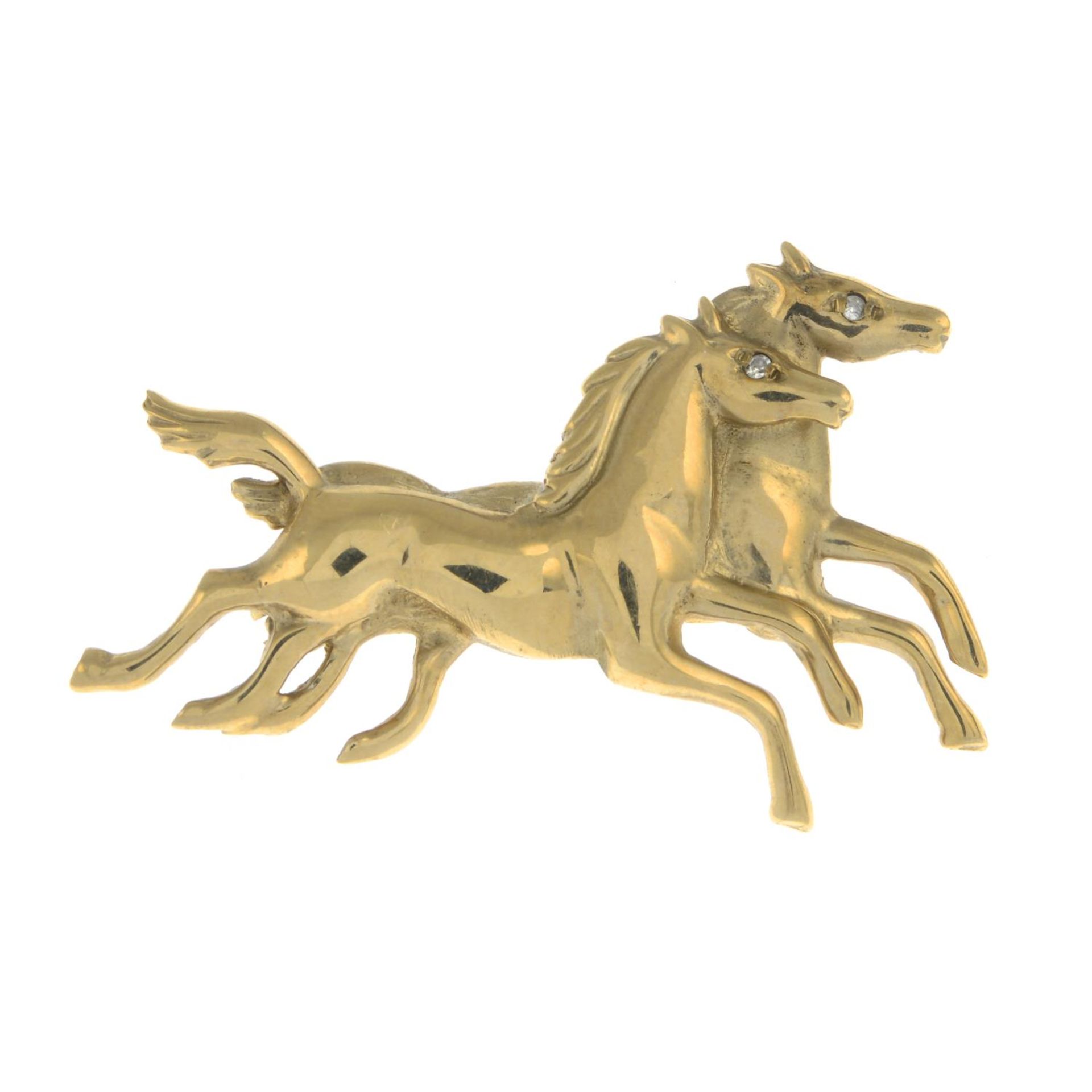 A 9ct gold brooch of galloping horses with diamond accents.Hallmarks for Birmingham.Length 4.8cms.