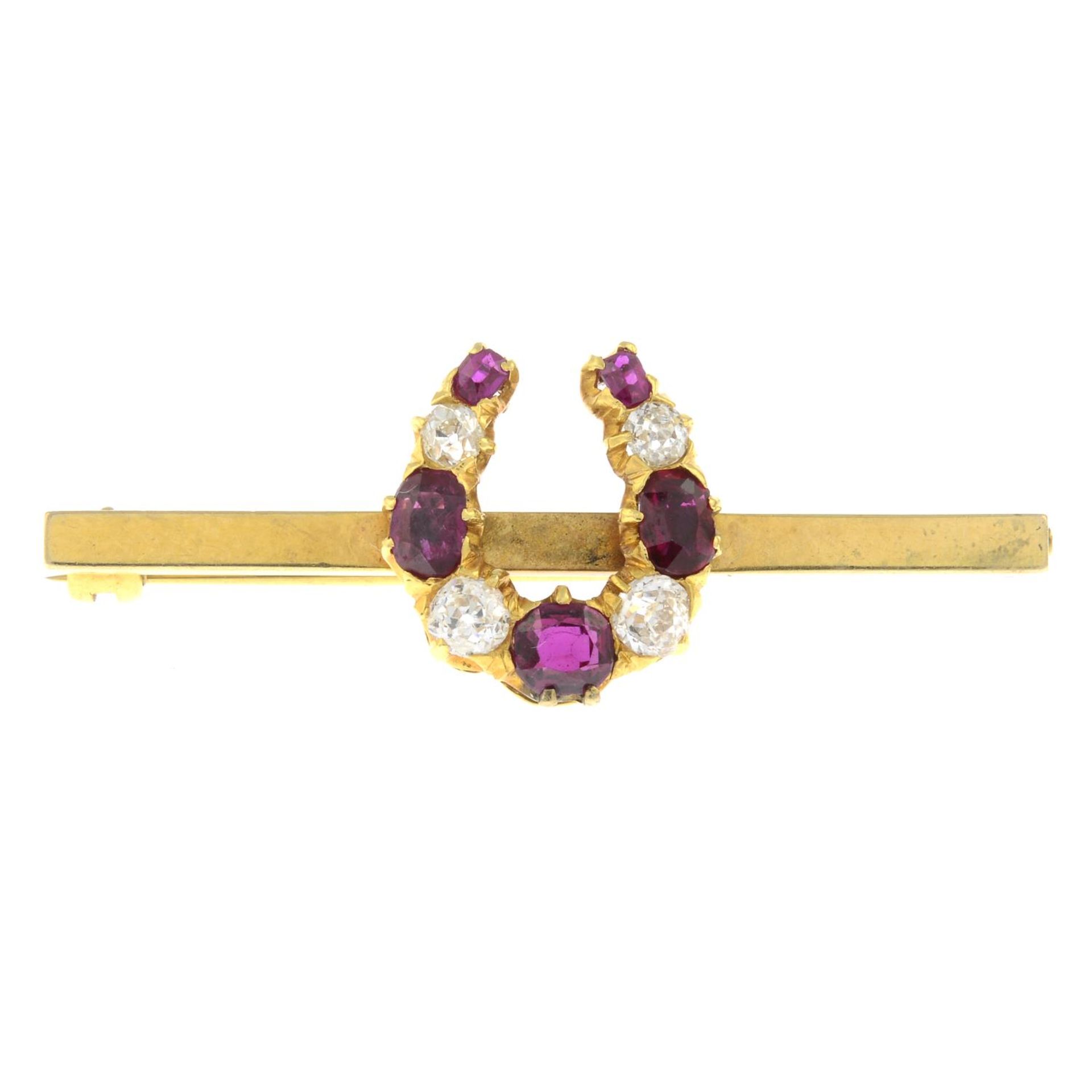 An early 20th century gold old-cut diamond and ruby horseshoe brooch.Estimated total diamond weight