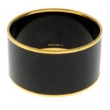 HERMÈS - a black and gold bangle.