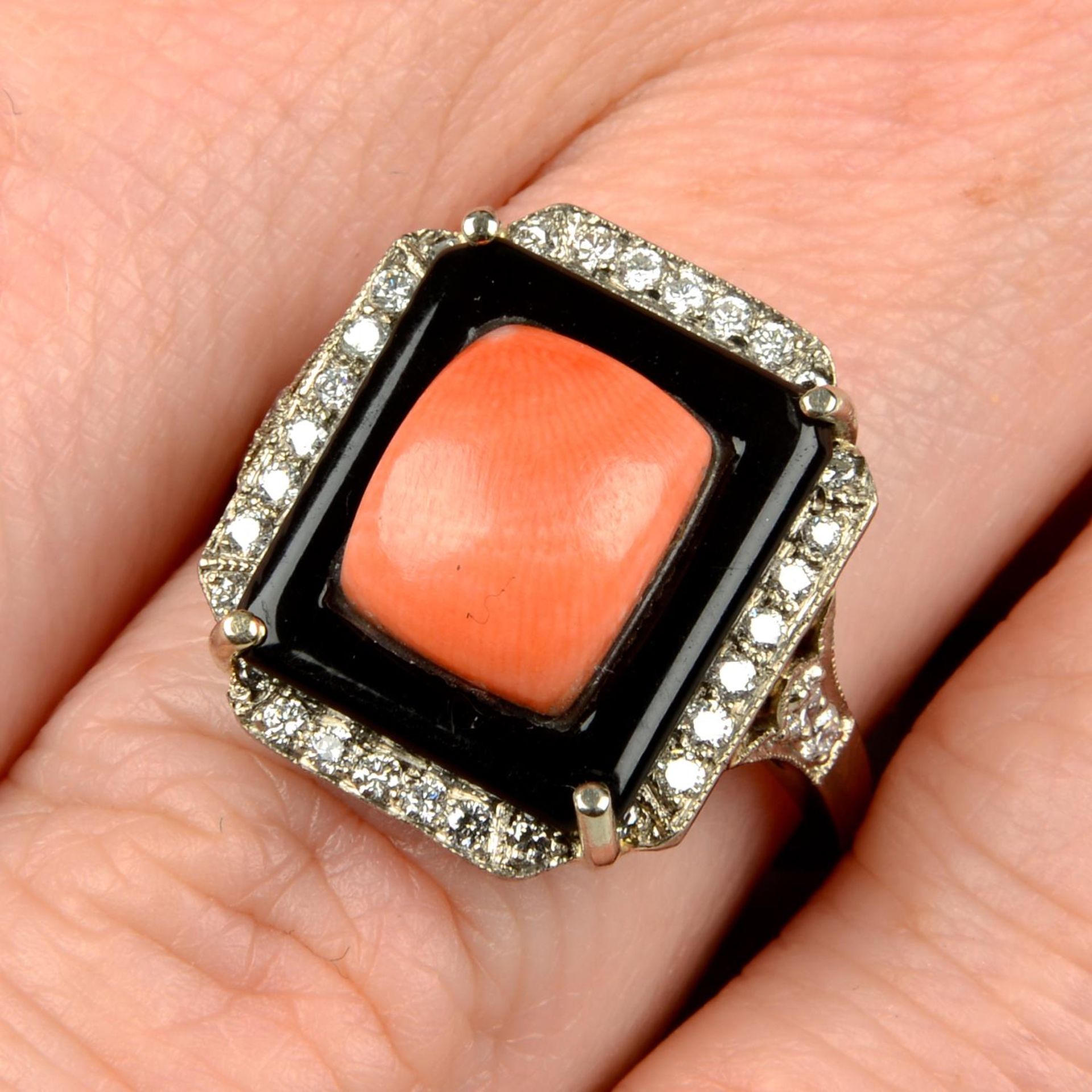A coral, onyx and diamond dress ring.Estimated total diamond weight 0.20ct,