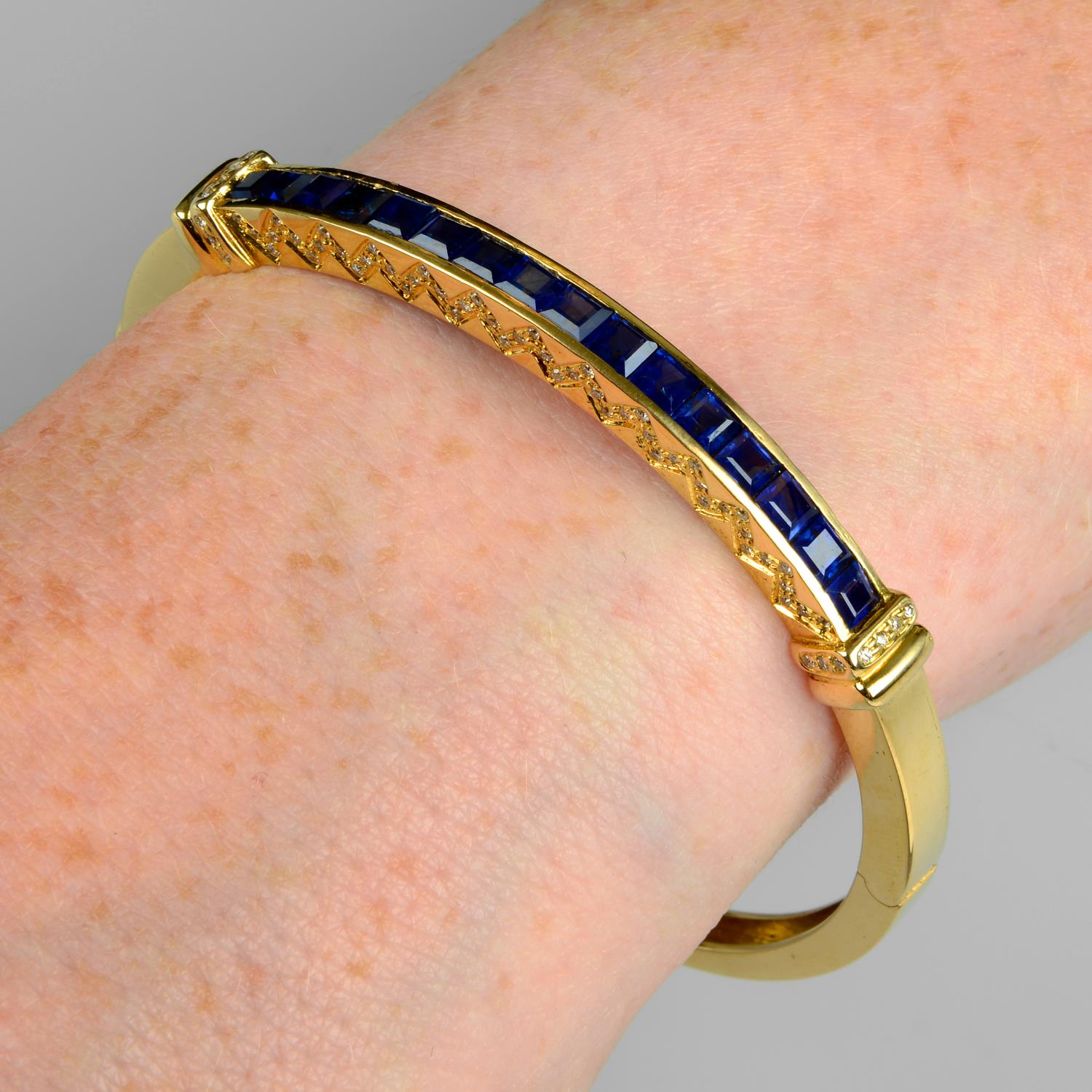 A sapphire and brilliant-cut diamond hinged bangle.Estimated total diamond weight 0.20ct.