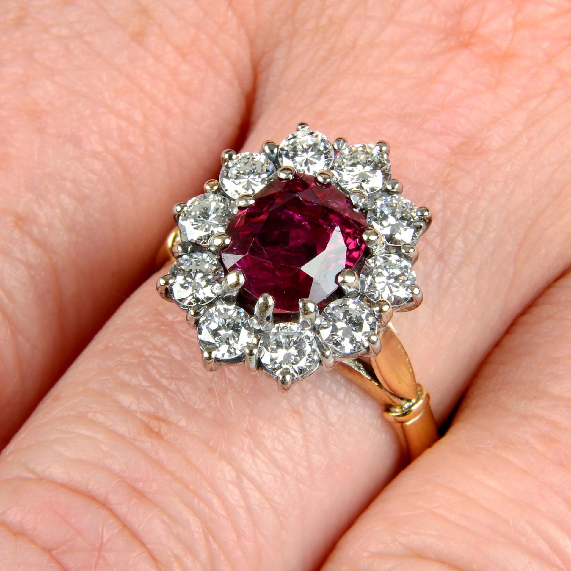An 18ct gold ruby and brilliant-cut diamond cluster ring.Ruby calculated weight 1.78cts,