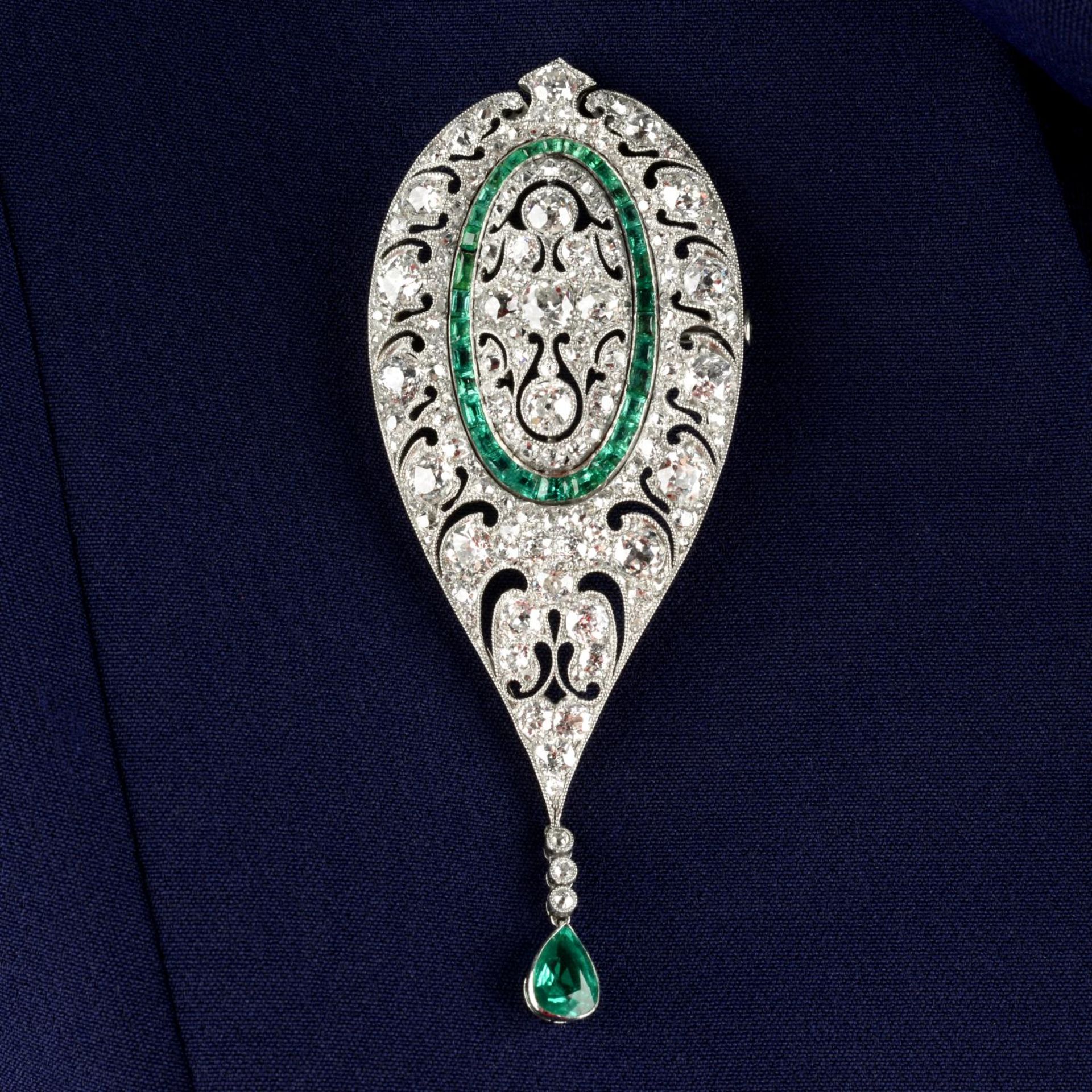 An Art Deco platinum, diamond and emerald, pierced brooch.