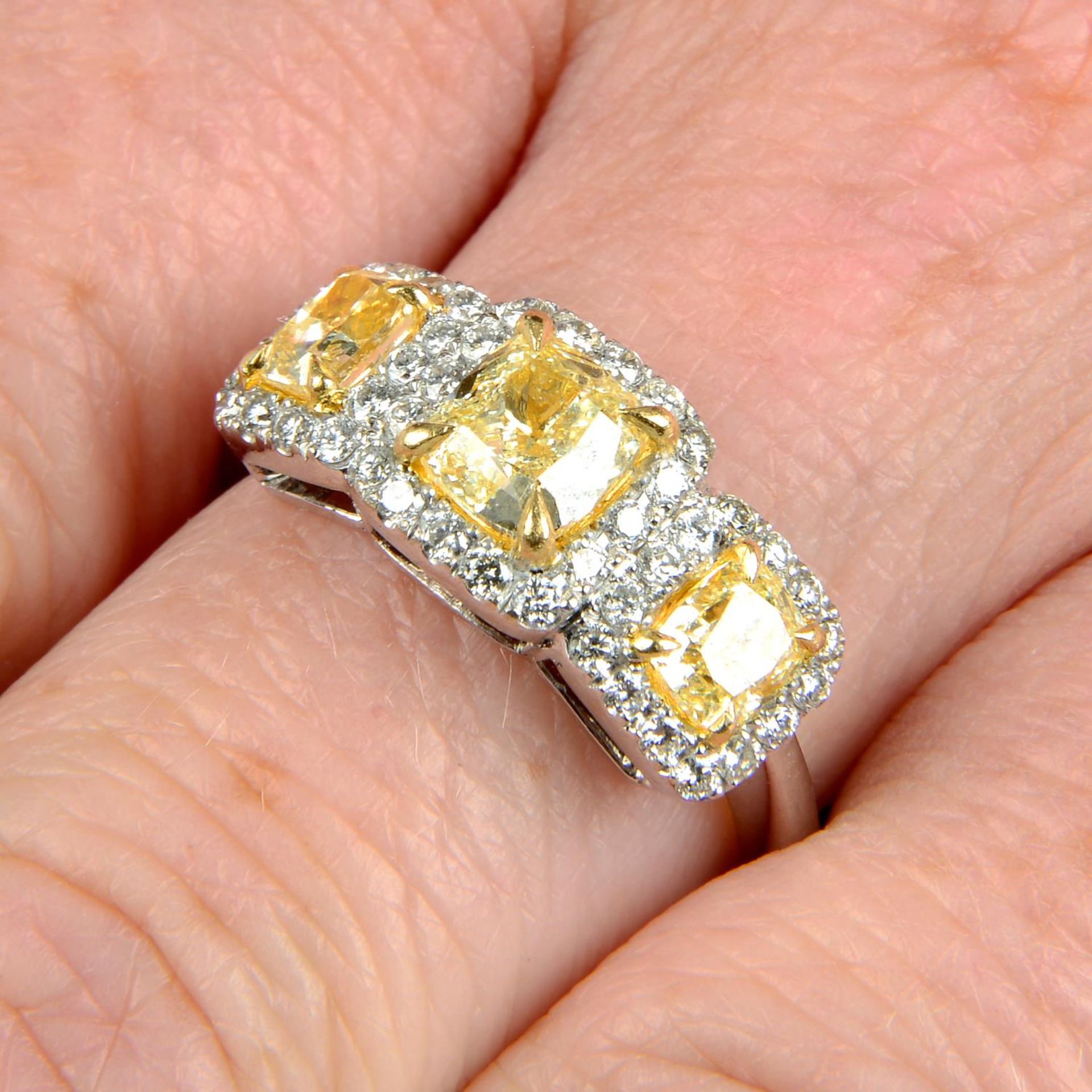 A 'yellow' diamond and diamond three-stone cluster ring.Estimated total 'yellow' diamond weight