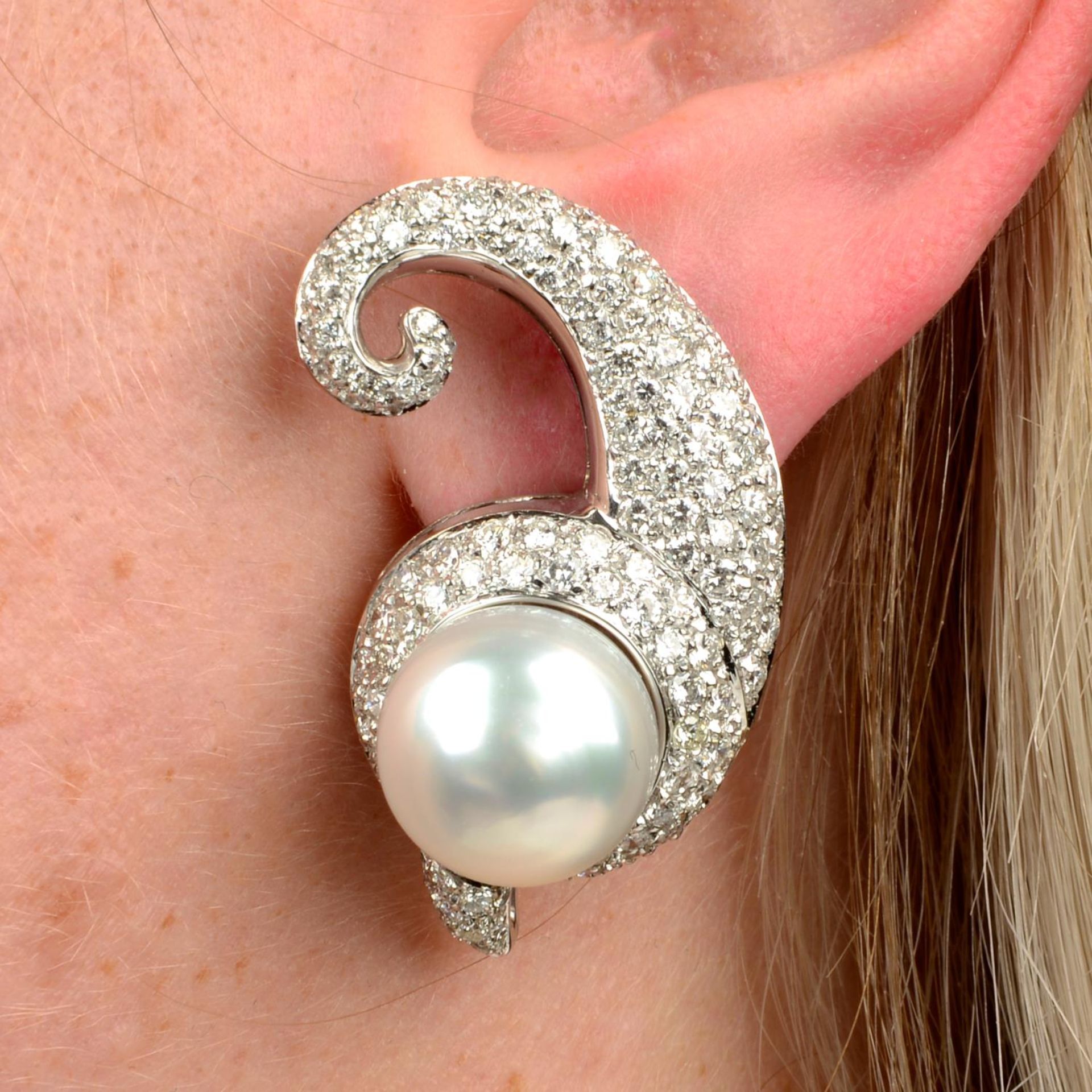 A pair of cultured pearl and pavé-set diamond scroll earrings.Estimated total diamond weight 4cts,