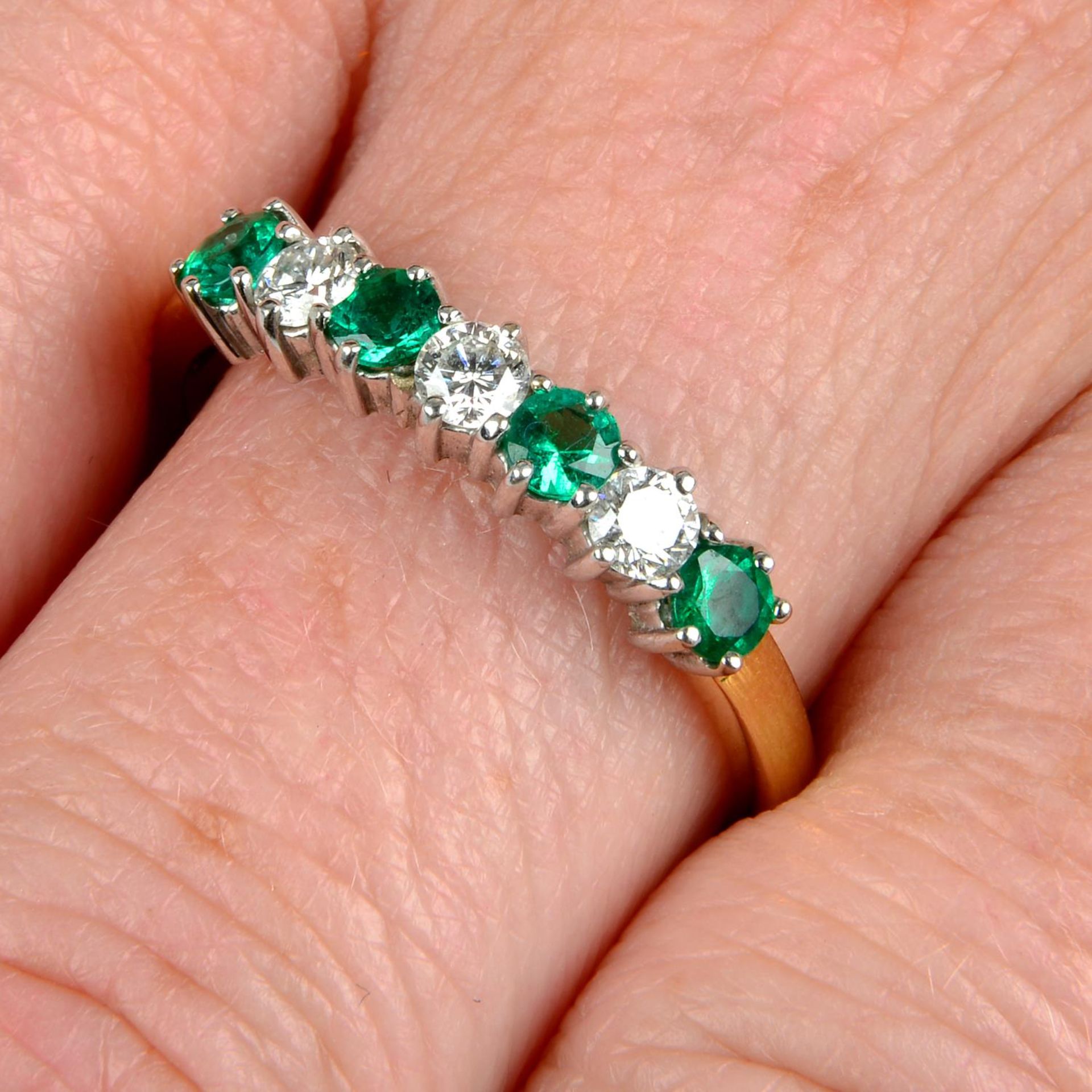 An 18ct gold alternating emerald and brilliant-cut diamond half eternity ring.Estimated total