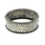 An early 20th century silver hinged bangle, with engraved foliate detail.Inner diameter 5.7cms.