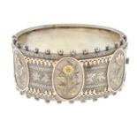 A late Victorian engraved hinge bangle with appliqué flower motifs.Inner diameter 6cms.