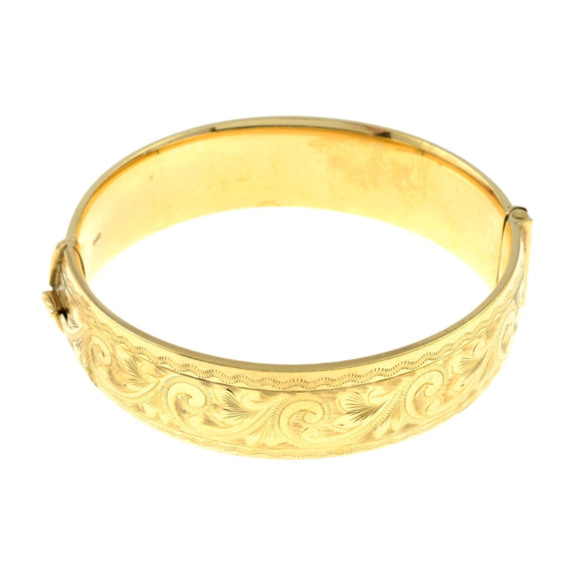 A 9ct gold engraved hinged bangle.Hallmarks for London, 1960.Inner diameter 5.9cms.