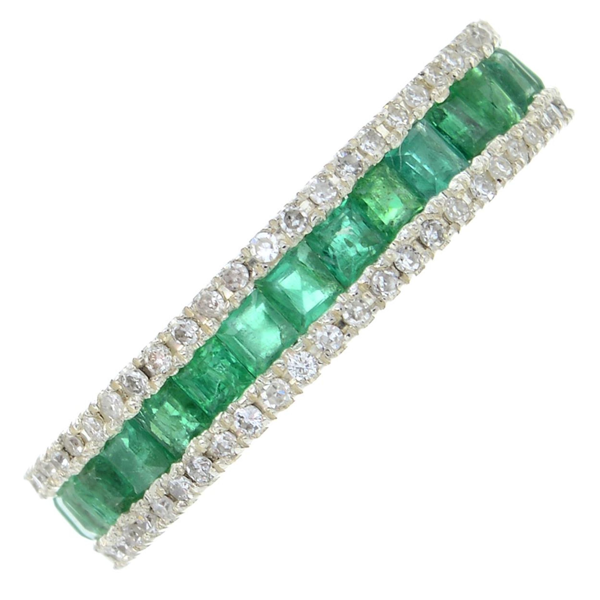 An emerald and diamond full eternity ring.Estimated total diamond weight 0.50ct.