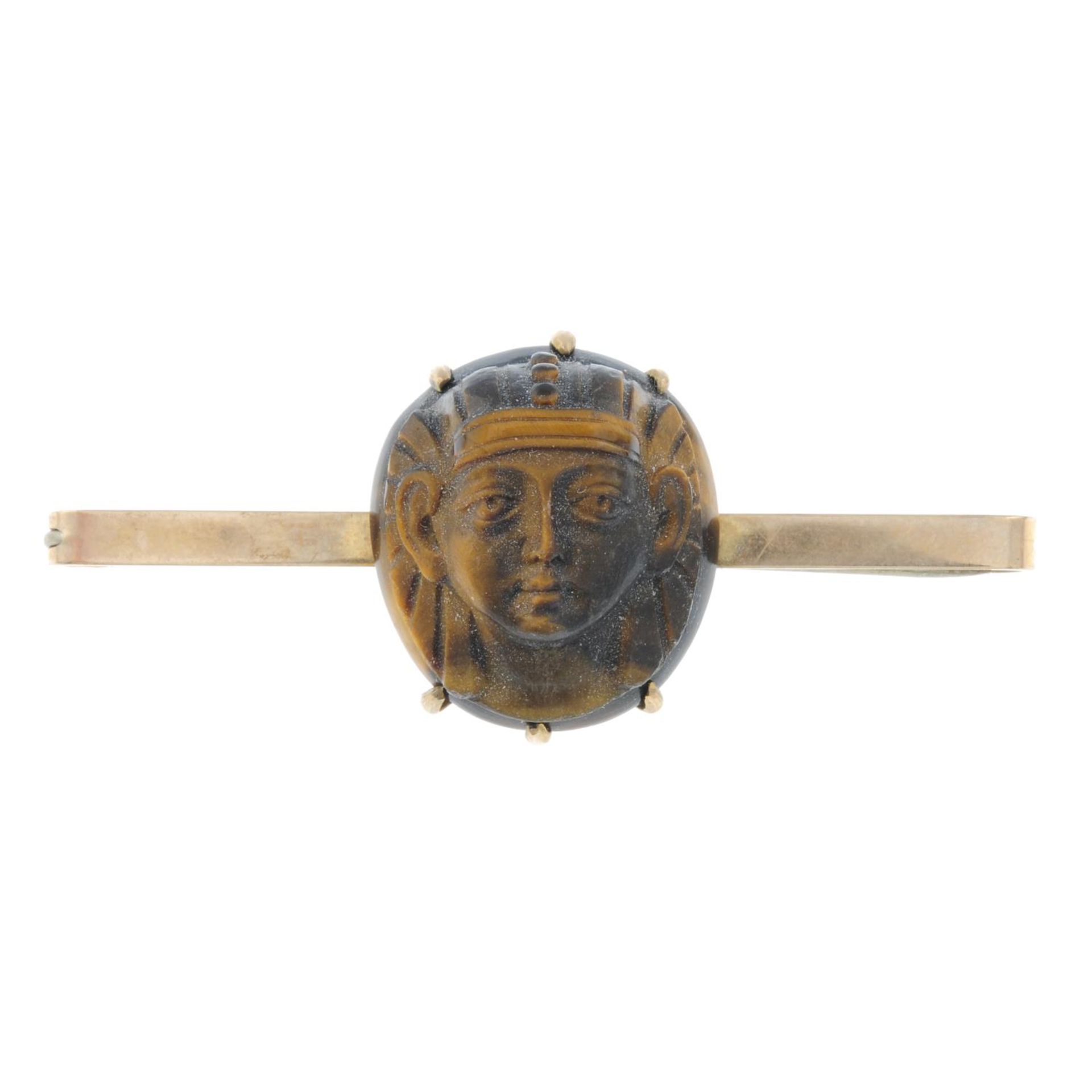 An early 20th century 9ct gold carved tiger's-eye Egyptian Revival pharaoh mask brooch.Stamped