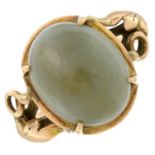 A jade cabochon dress ring, with foliate shoulders.