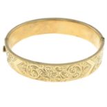 A 9ct gold early 20th century engraved bangle, with safety chain.