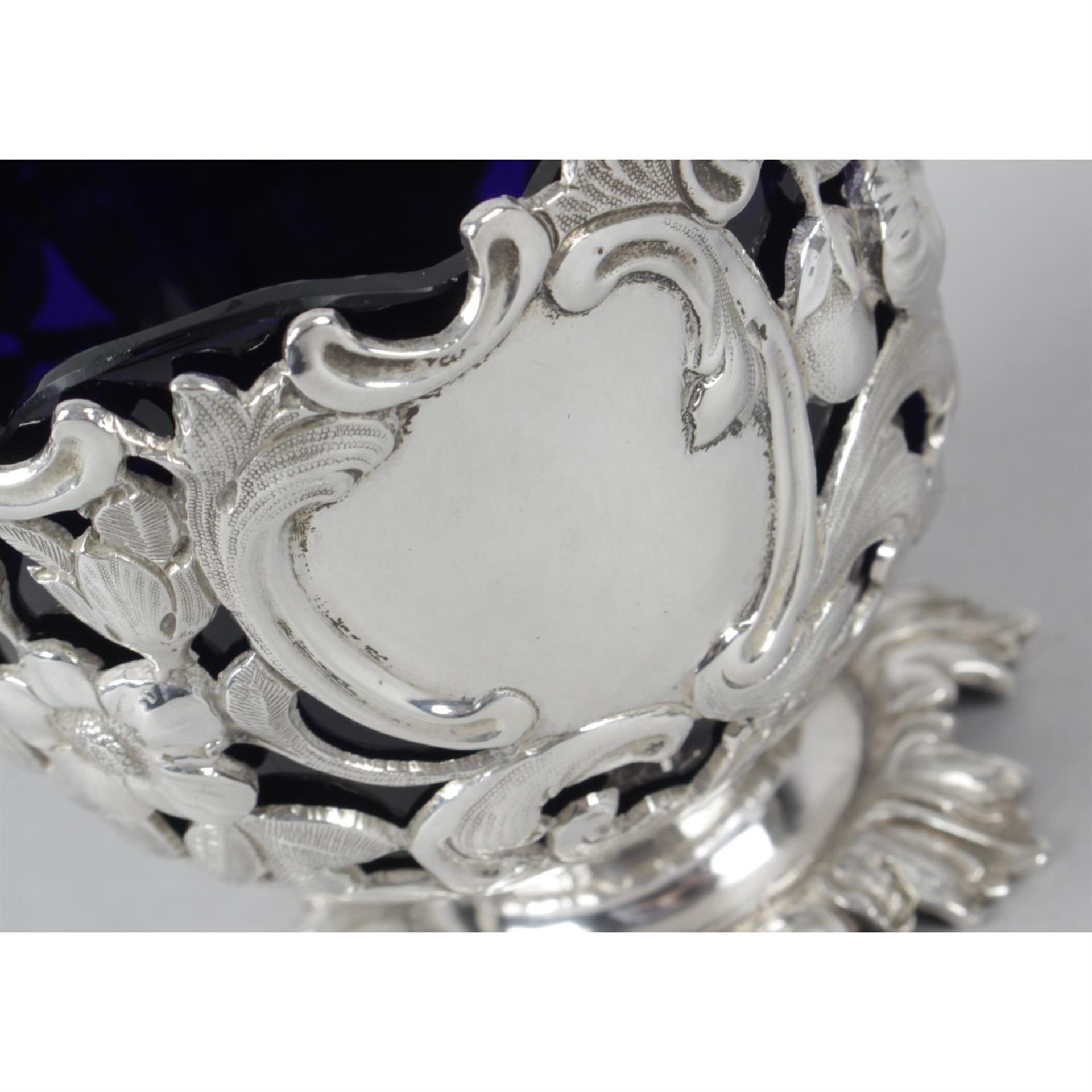 An early Victorian silver pierced and swing-handled sugar basket with blue glass liner. - Image 2 of 3