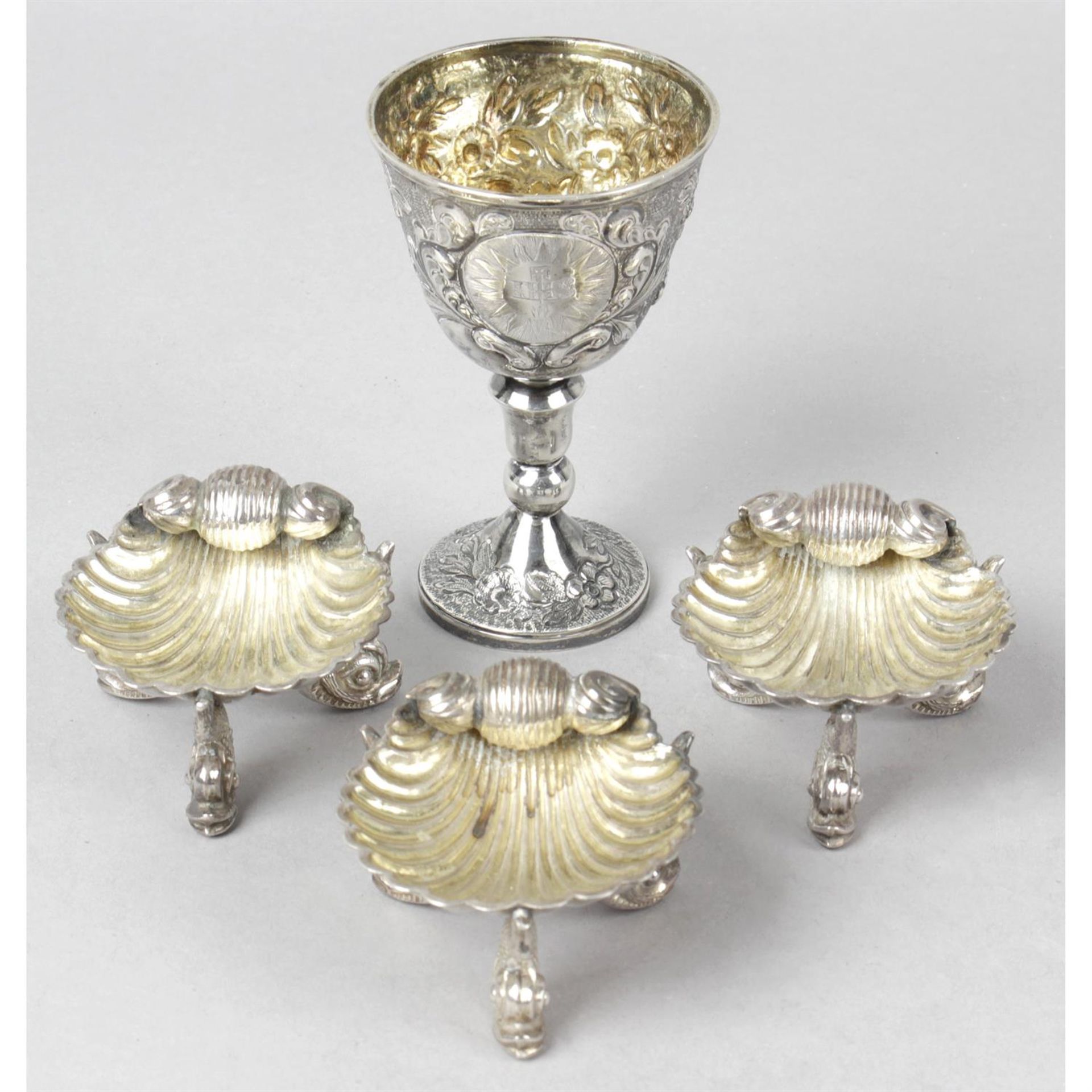 A George IV silver communion goblet, together with three late Victorian silver shell salts. (4).