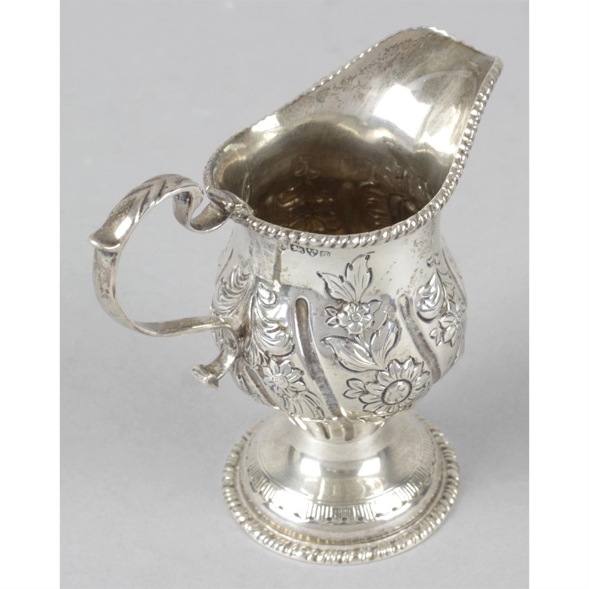 An Edwardian silver floral embossed pedestal cream jug. - Image 2 of 3