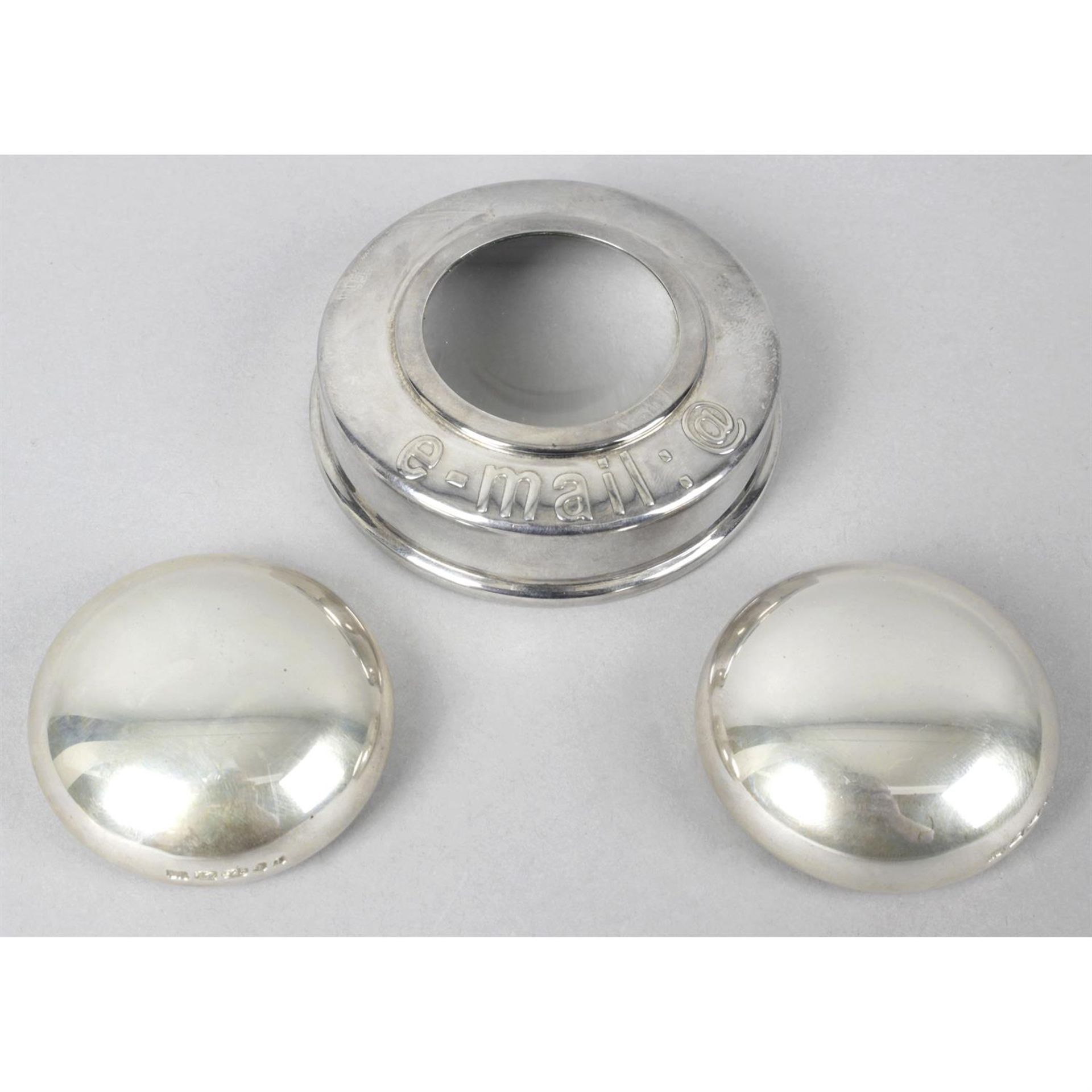 A pair of silver domed paperweights and a round silver magnifying glass. (3).