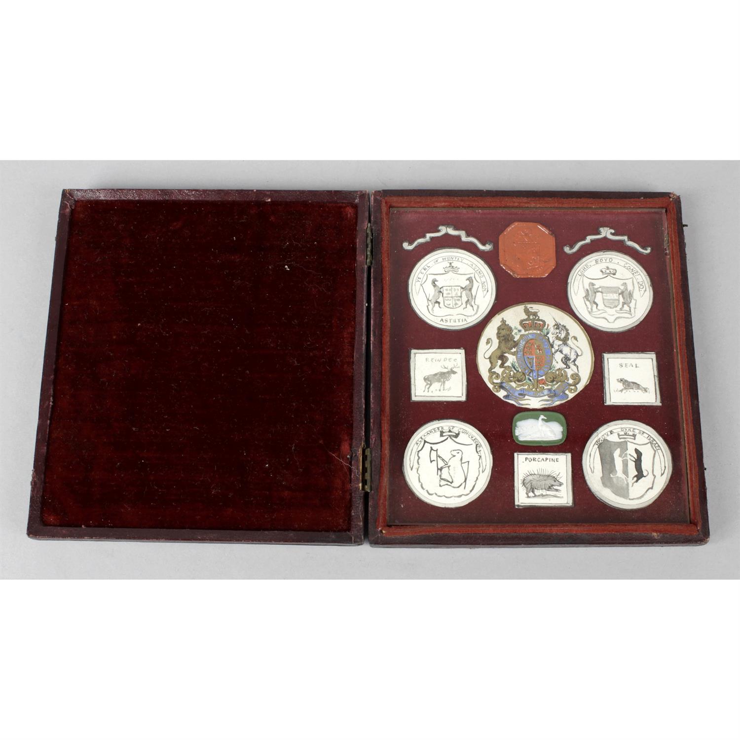 A red leather hinged case containing a wax seal and armorial crests.